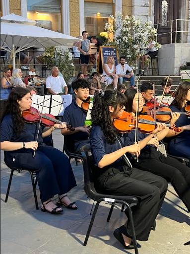 A group of people sitting and playing their respective instruments.