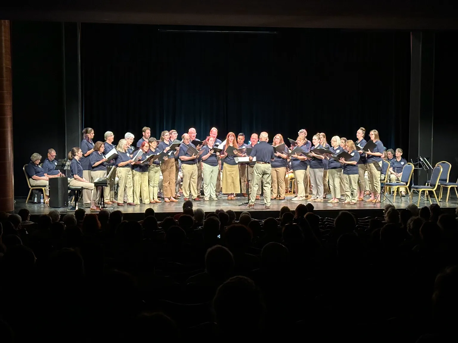 Adult musicians performing together on stage during the American Music Abroad Community Tour.