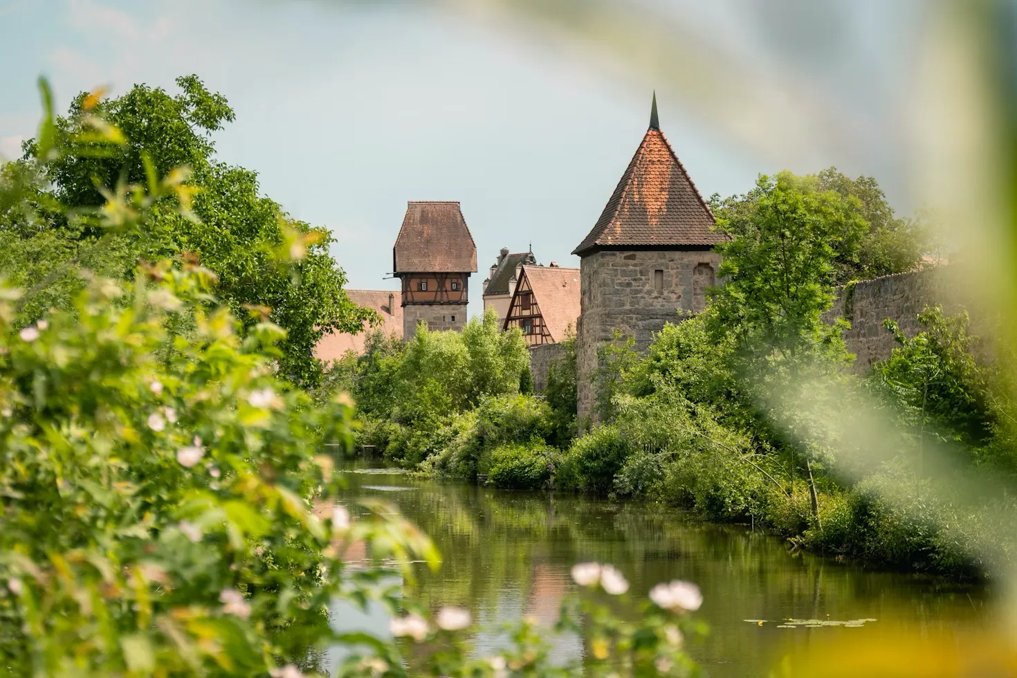 A historic castle along a river in Dinkelsbühl, Germany, surrounded by medieval town walls.