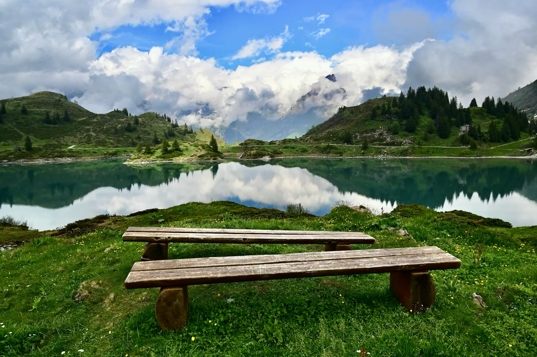 A bench overlooking a lake with alpine mountains in the background in Engelberg, Switzerland.