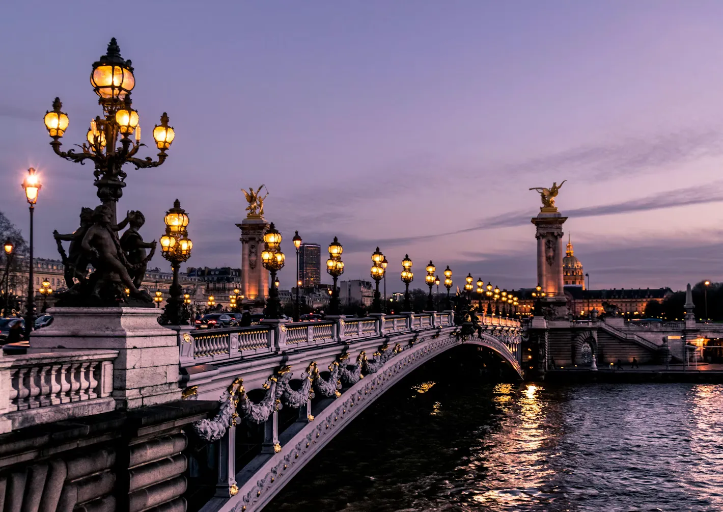 Evening view of a bridge over the Seine River in Paris, with lights reflecting on the water.
