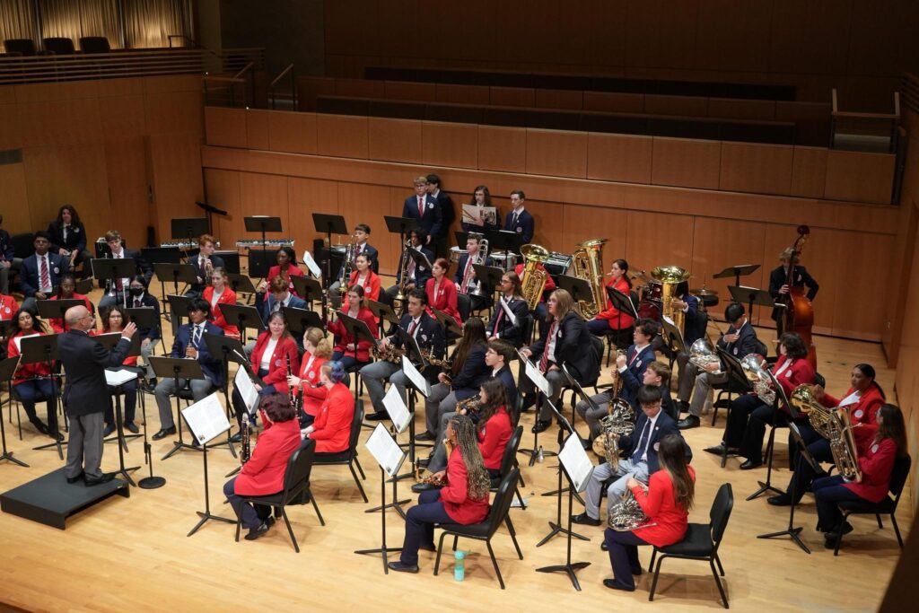 High school musicians performing together under conductor.