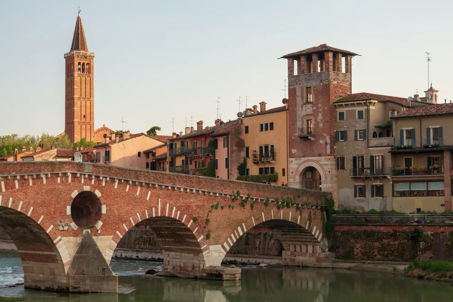 A bridge spanning a river in Verona, Italy, with historic buildings along the banks.
