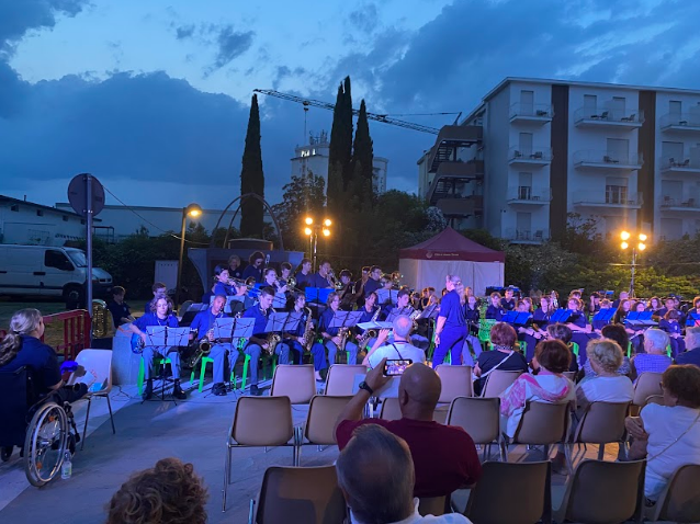 Student music ensemble performing an outdoor evening concert for a seated audience during an American Music Abroad tour.