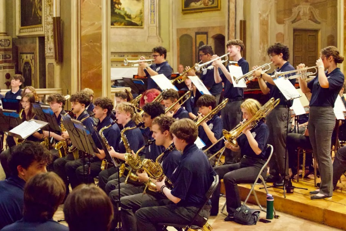 Student musicians performing in a live ensemble concert with brass and woodwind sections during an American Music Abroad performance tour.