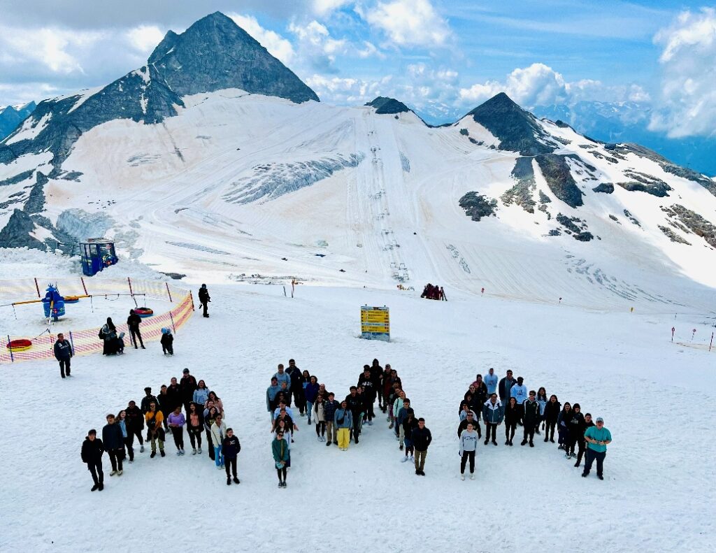 Group of students standing together in a snowy alpine mountain setting during an international educational travel experience.