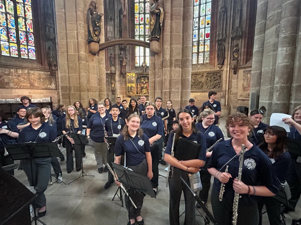 Collegiate musicians share a memorable moment inside a historic European church, reflecting the community and cultural connections built throughout the All-American Honors Collegiate Tour.