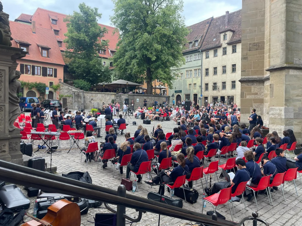 Students perform outdoors in a European setting, bringing their music to an audience beyond their hometown.